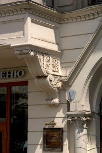 Просп. Шевченка, 21. Фрагмент фасаду в рівні І-го пов. Ліпний кронштейн еркеру (зліва), фрагмент вхідного порталу справа.